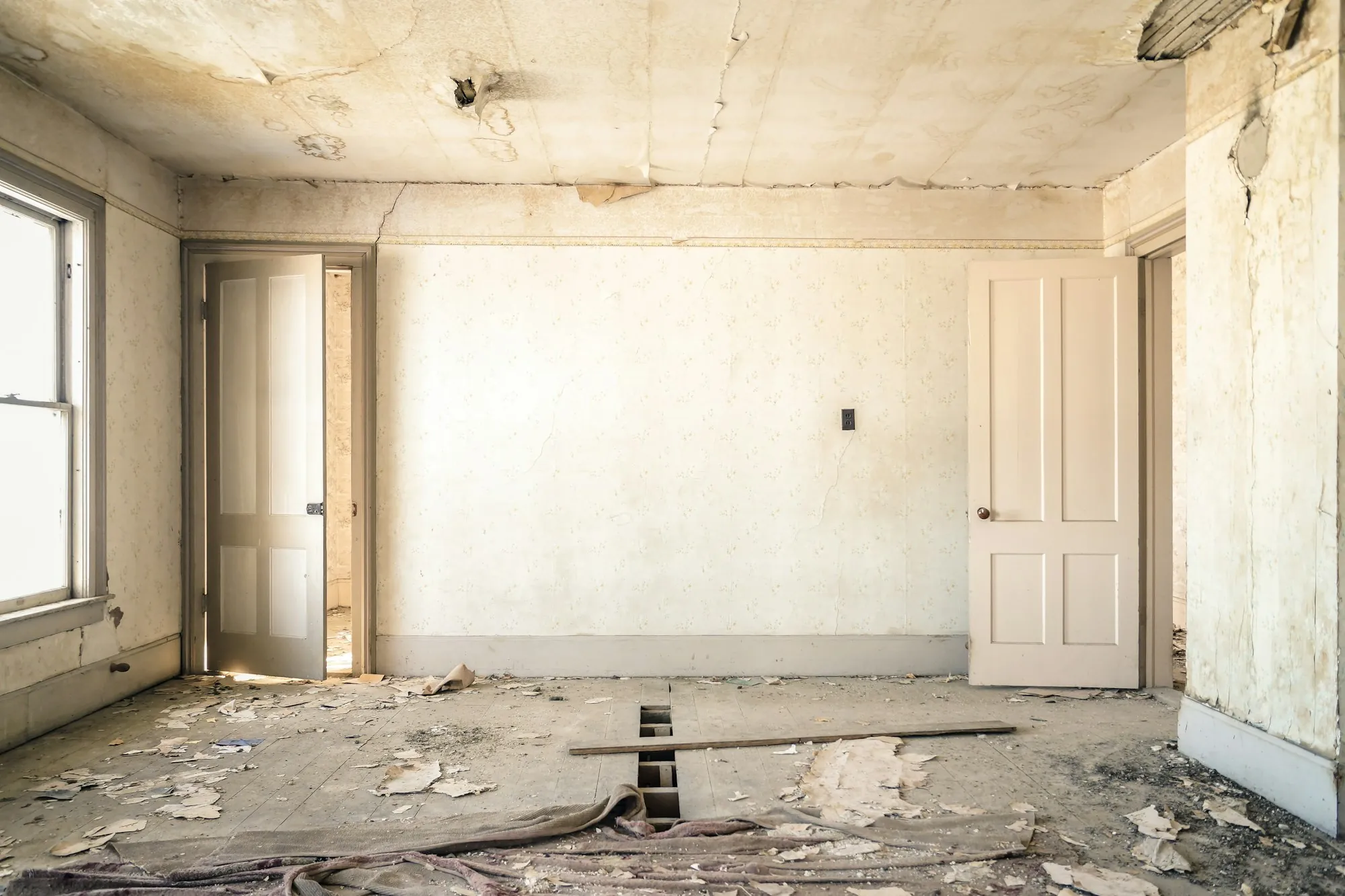 Gutted room with bare plaster walls and an open ceiling ready for a full renovation